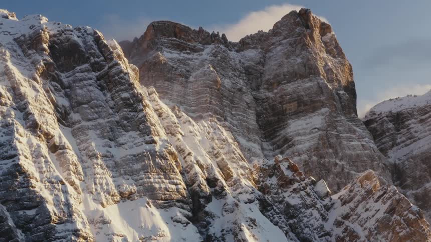 A jagged mountain ridge and cliff with snow on a sunny day