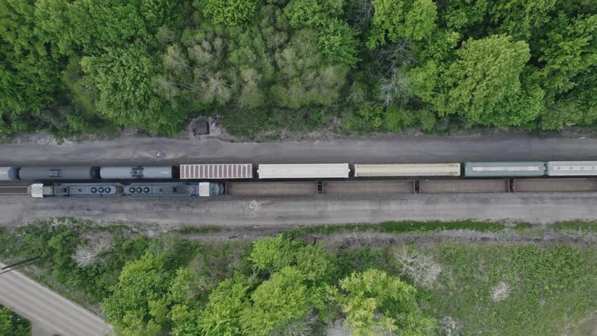 A long train travels along a railway in the countryside during the day