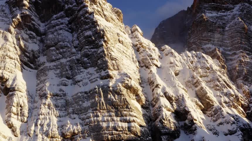 The sun shines down on a tall canyon dusted with snow