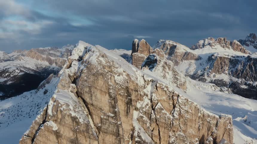 Snow cover accents a mountain ridge and peaks under a cloudy sky