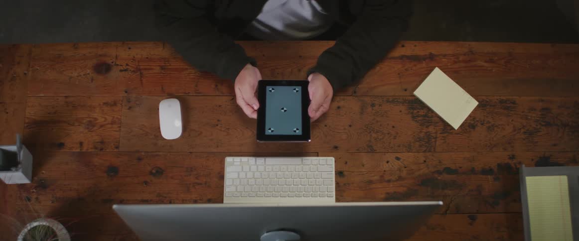 A person holds a computer tablet while sitting at a desk