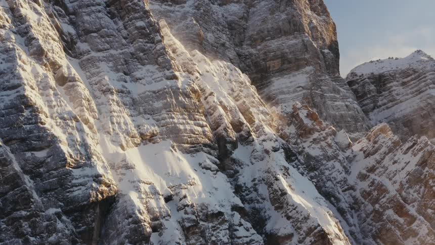 Snow clings to a jagged mountain rock face in lines