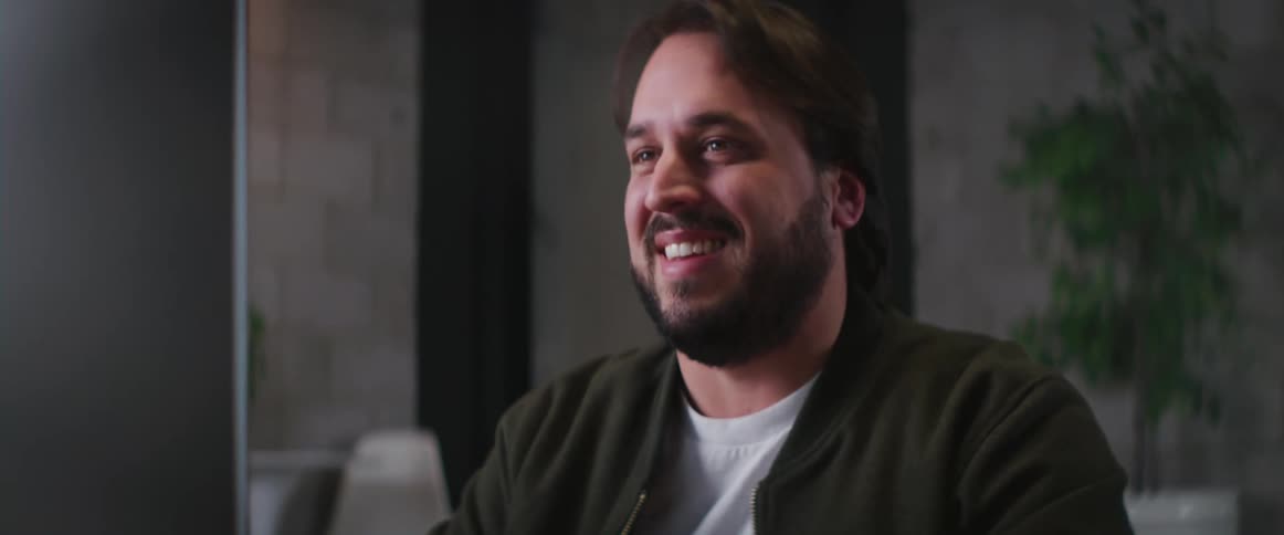A man smiles while typing on a computer keyboard at a desk