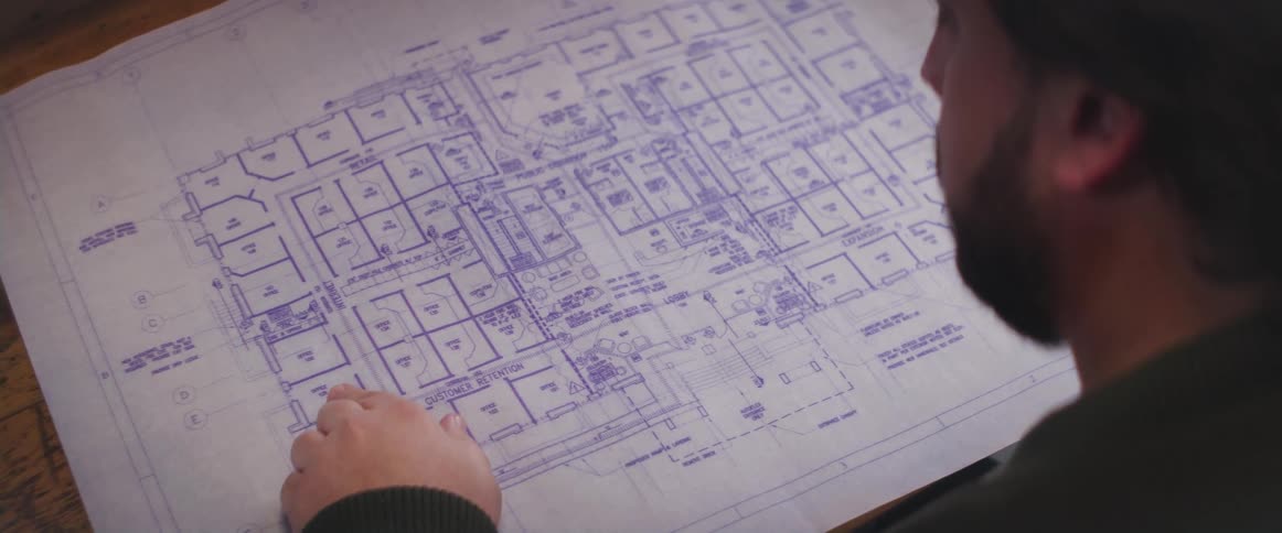 A man unrolls and examines a blueprint