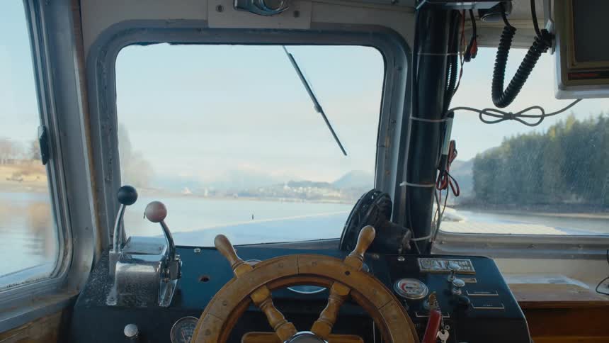 A ships navigating equipment and a view through the window of the river and trees