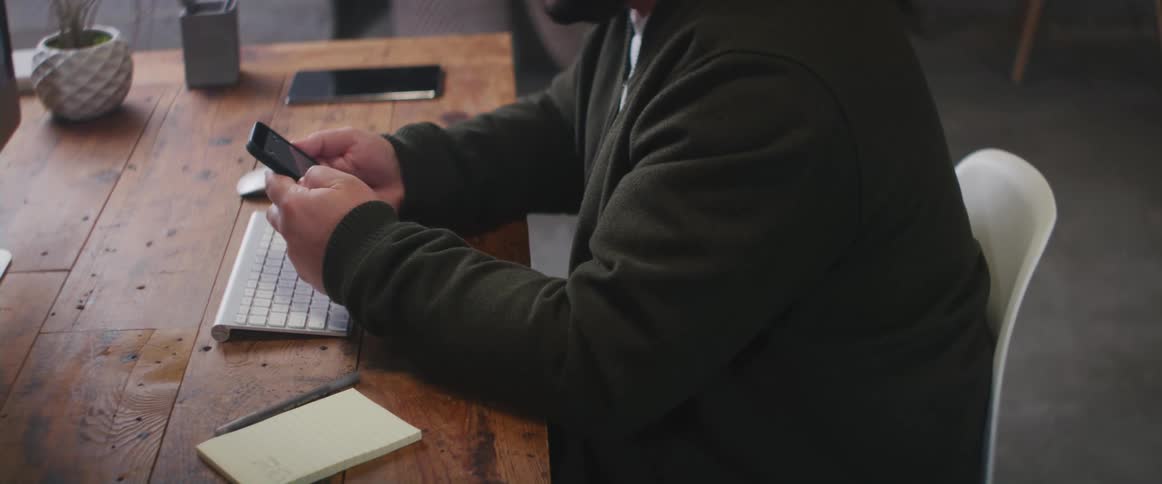 A man is using his phone at the desk