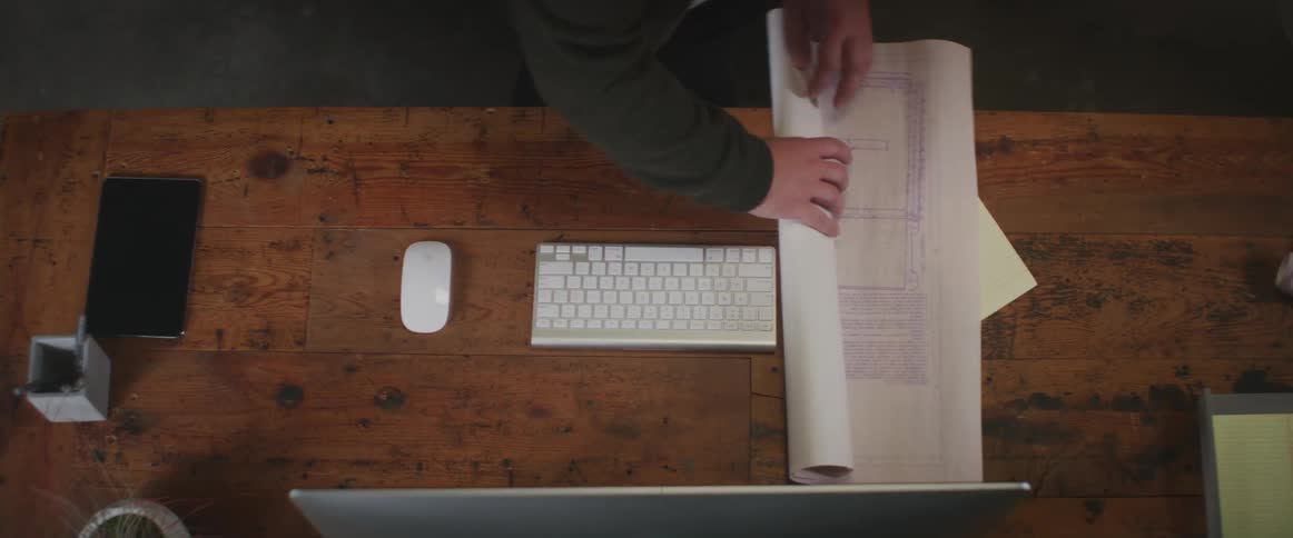 A person rolls up blueprints on the desk