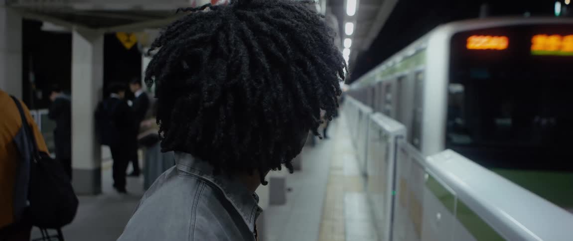 Man holds his arm up so the train will stop but the train continues on the track at night