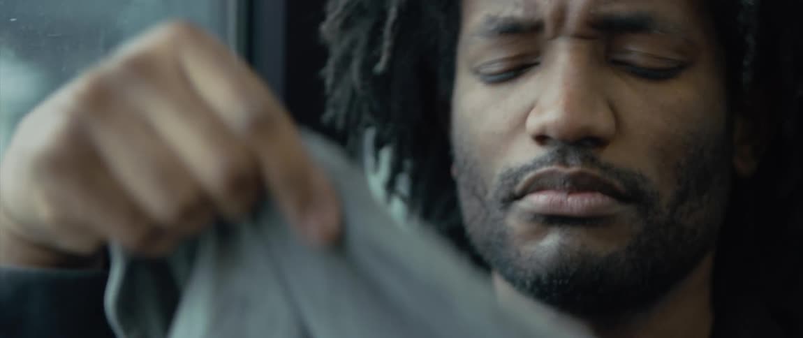 An upset man riding public transportation covers his face with a piece of clothing
