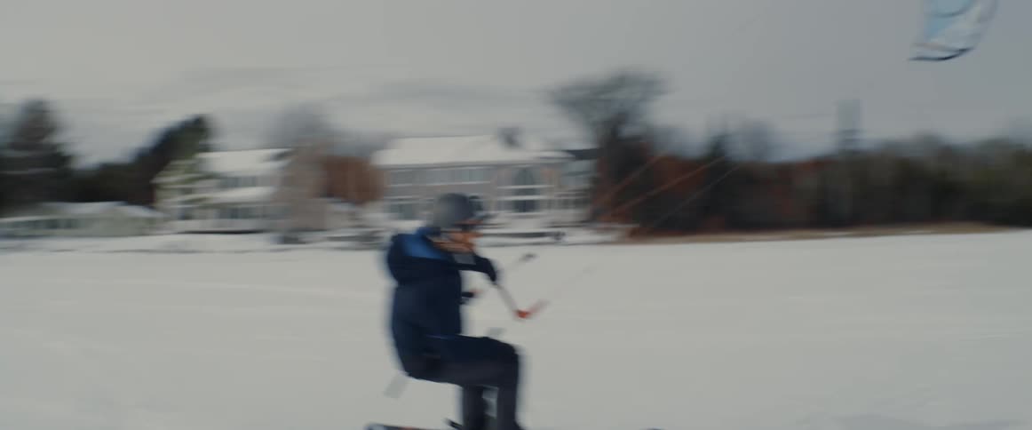 A man snowkiting on a snow covered frozen lake