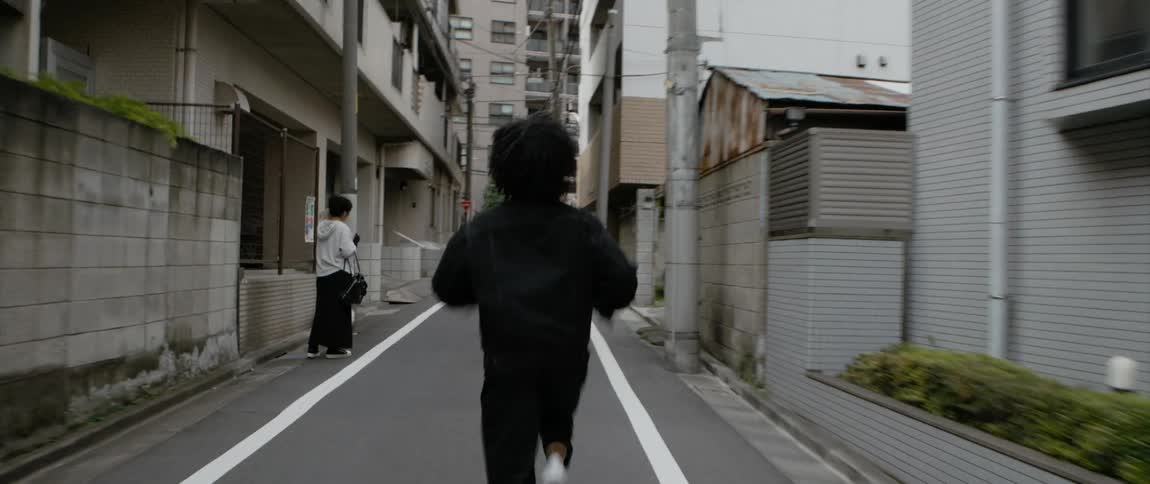 A person jogs along a narrow city street during the day