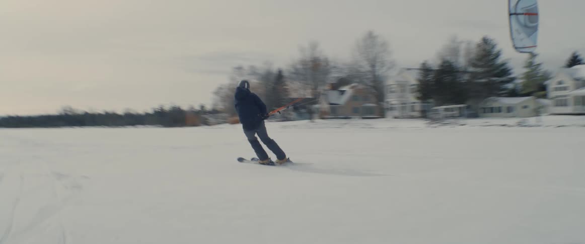 A person on skis holds a cords connected to a kite that they are using to pull them