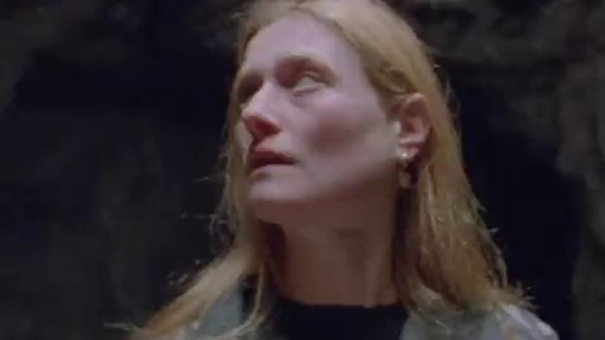 A woman standing in a cave near the entrance while light flashes and strobes