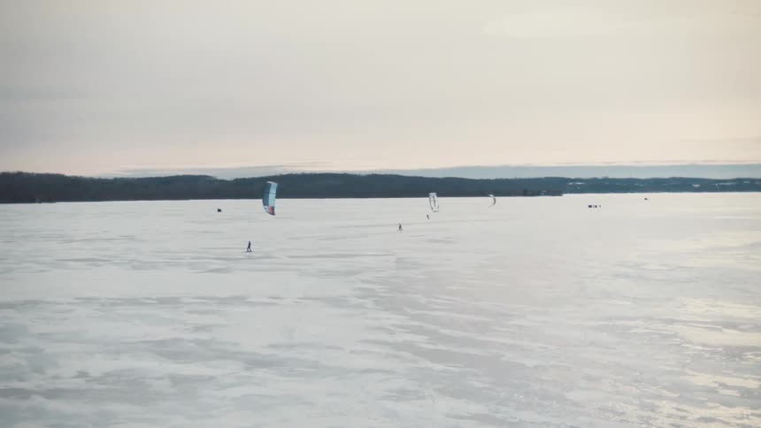 Skiers speedriding on the snowy field as mountains sit in the distance