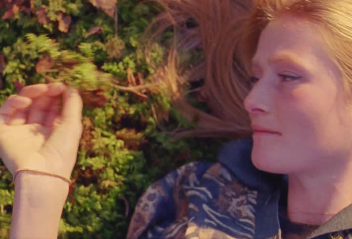 A woman is laying down in the grass outdoors at dusk