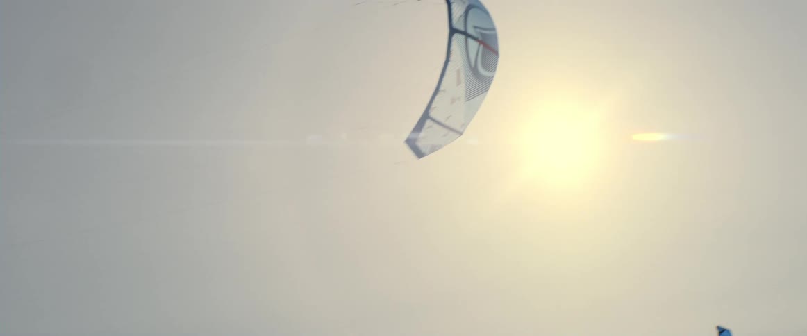 Paragliding stunt kites move through the sky on a sunny day