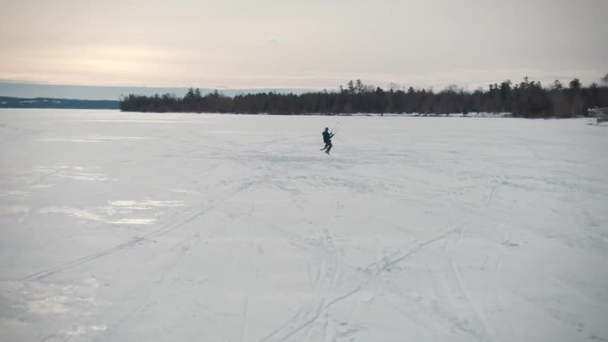 Person ski glides across ice on frozen water near houses