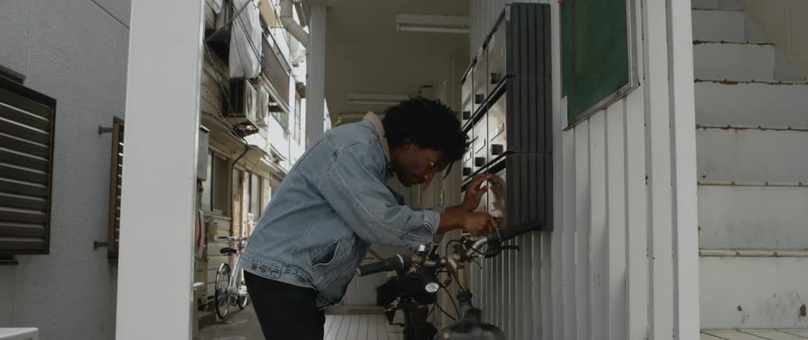 A young man inspects a cluster of mailboxes to figure out which one his key will work on