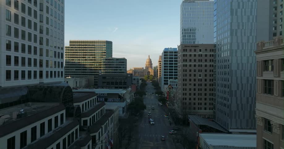 A road through a dense metropolis leading towards a government building in the distance