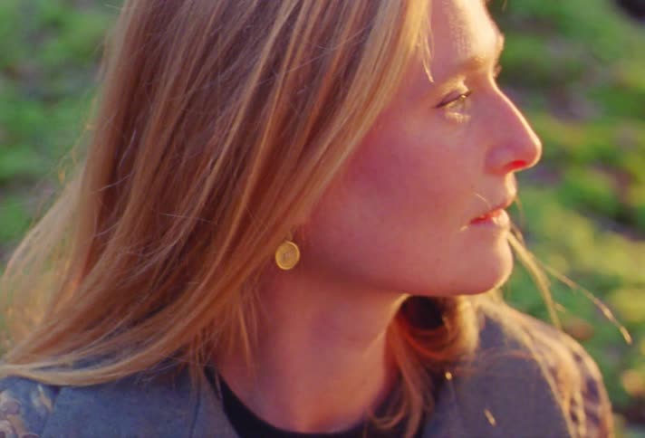 A woman sits up from the grass