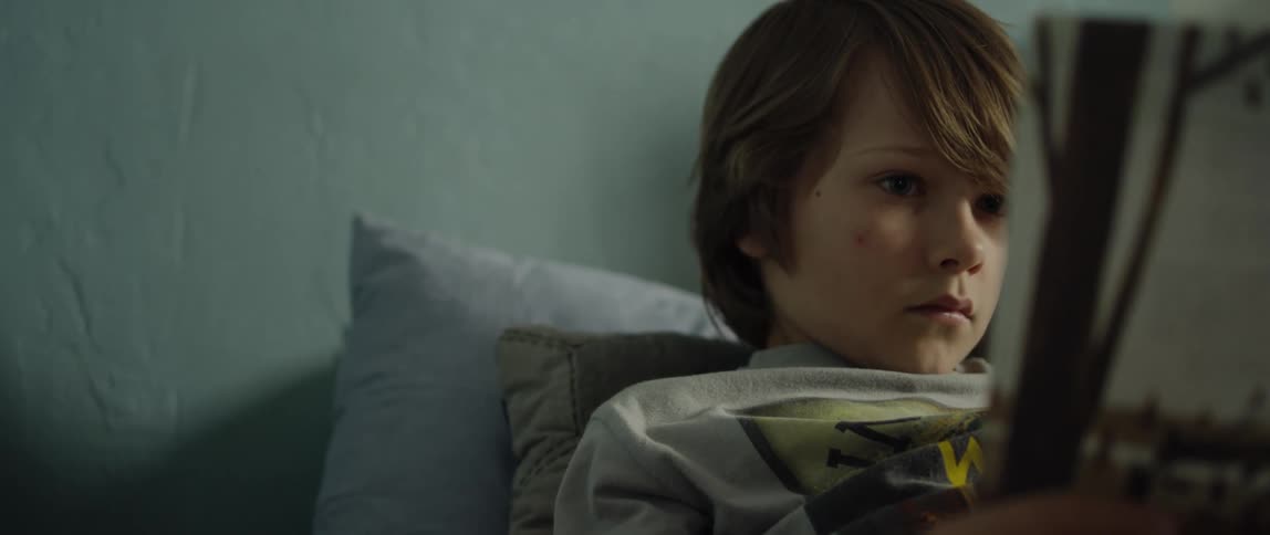 Boy reclines against pillows reading a book