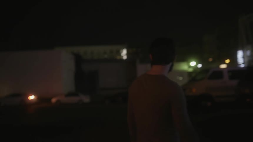 A man walks in a lot at night in a city