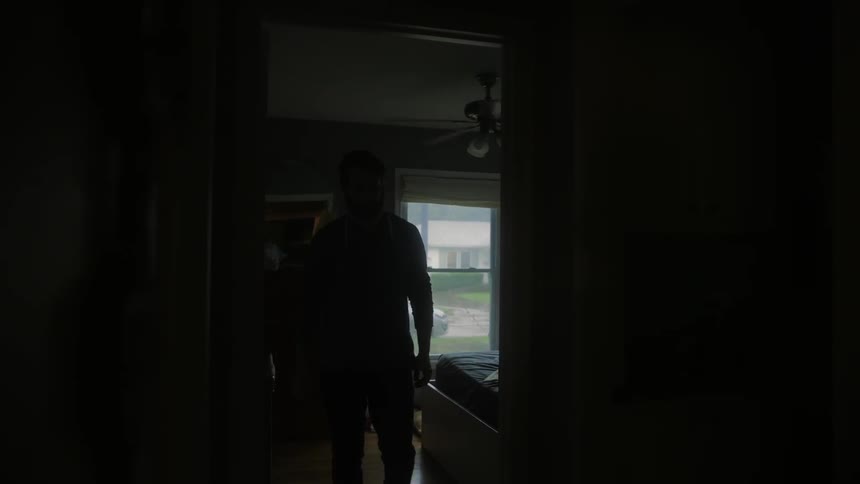 A man walks through a dark house