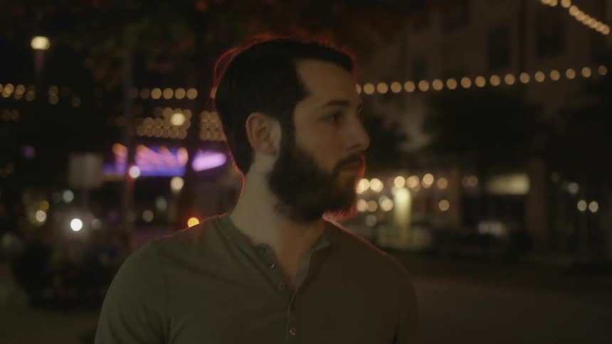 A man is walking outside at night as a truck with flashing lights drives up