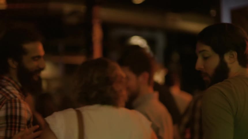 A man takes a drink then walks through a club