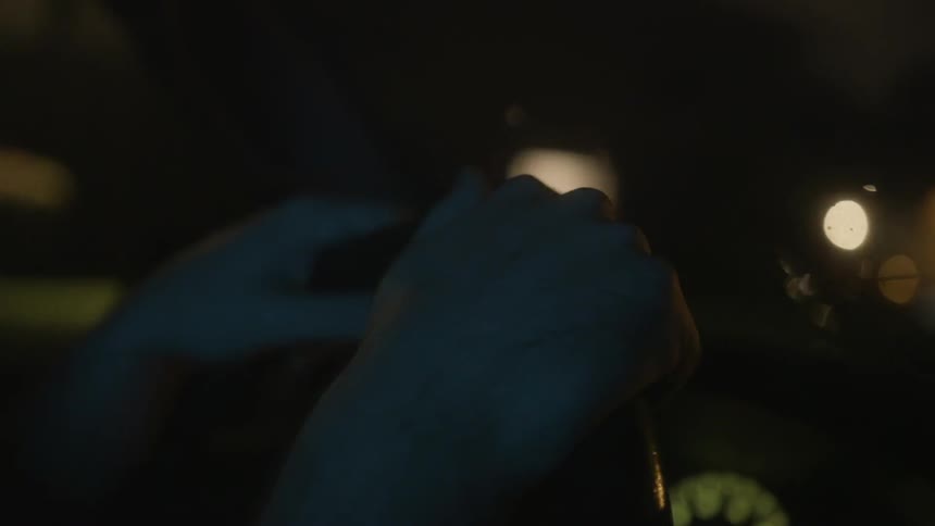 Close up of two hands steering a car wheel at night