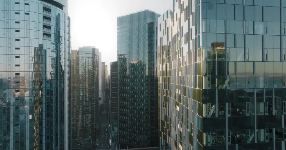 The reflections of the sky and nearby buildings shimmer on the surface of high rise towers