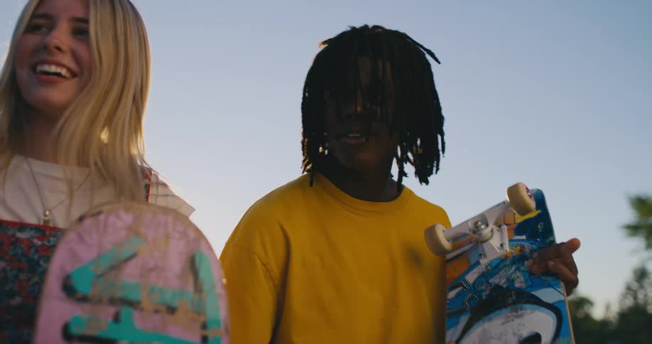 A group of friends sit at a park with their skateboards