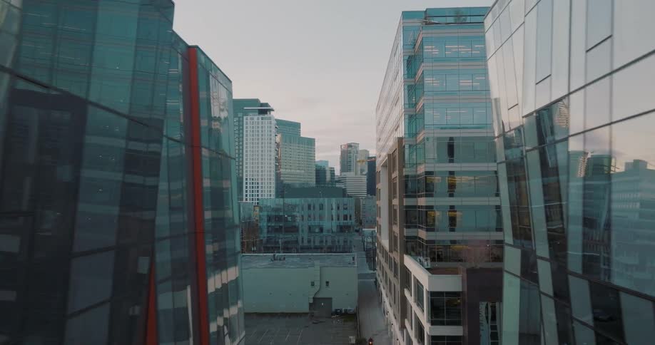 Flying through the narrow breezeway of a modern biotech complex to reveal other city buildings beyond