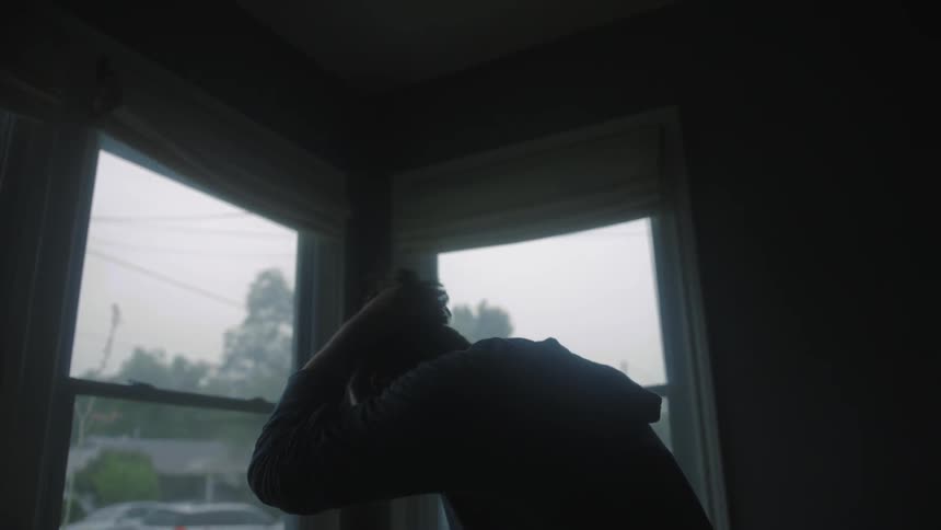 A man is standing near some windows in a home