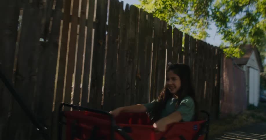 A woman pulls her daughter in a wagon through a neighborhood