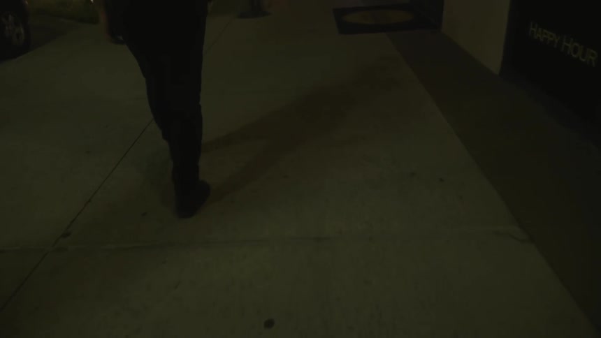 A person is walking on a sidewalk at night