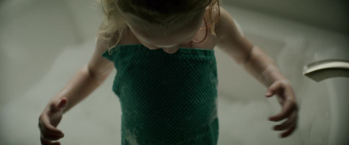 A little girl is standing in a bathtub with a towel wrapped around her and she is wiping her hands on the towel