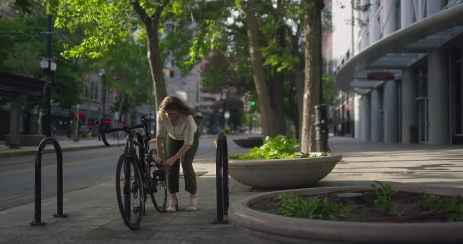 A woman unlocking a bicycle outdoors