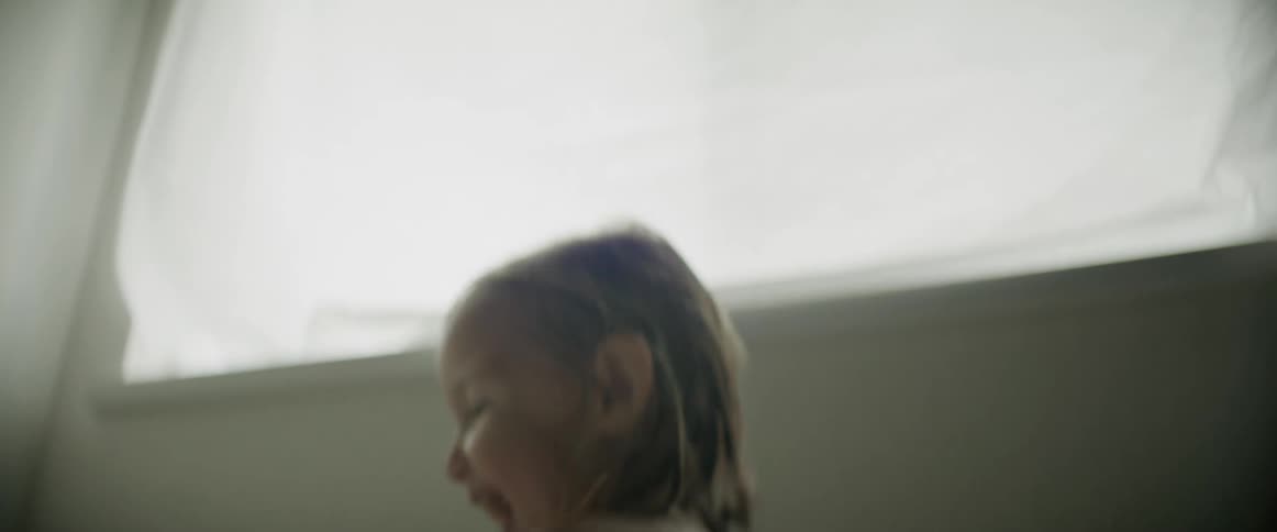 Girl with wet hair smiles while jumping around near window