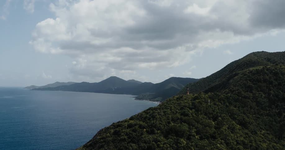 A lighthouse sits on the peak of a promontory along the coast