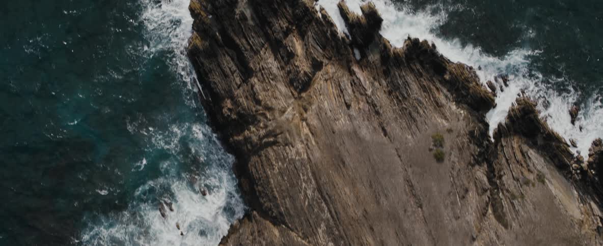 Waves crash onto rocks below a cliff