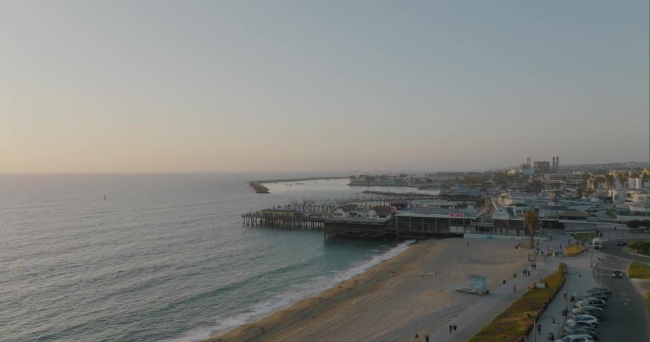 Aerial view of white sand beach next to the ocean and harbor at sunset