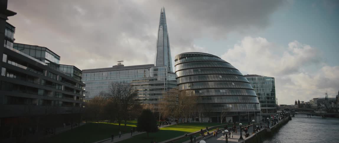 People move along walkway in London between The Shard and City Hall building on River Thames