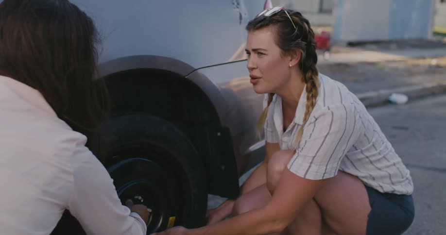 Two women changing a tire on a car