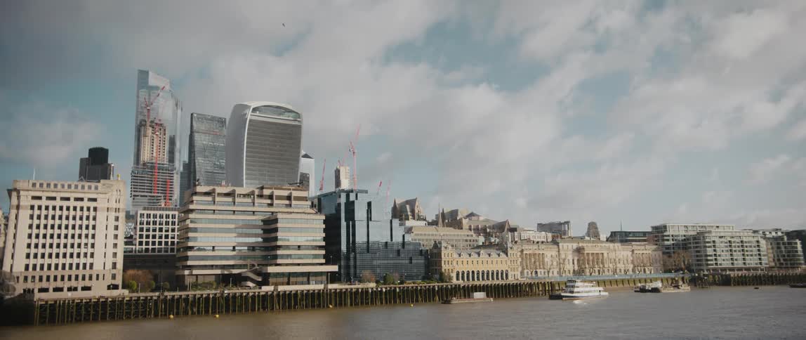 City skyscrapers next to River Thames in London against with partly cloudy sky