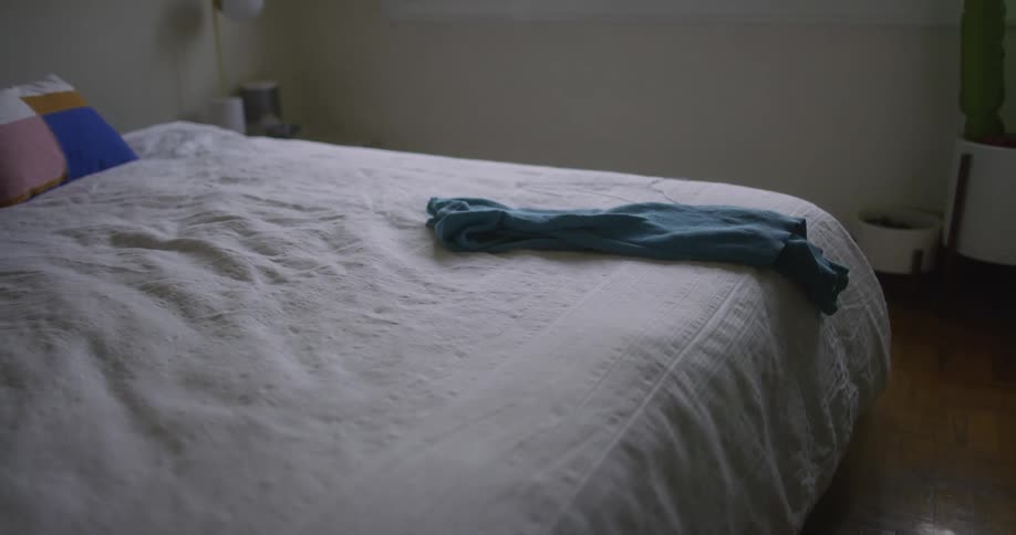 A man places clothes in a pile on his bed