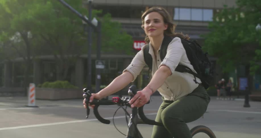 Woman bicycles through intersection near bank