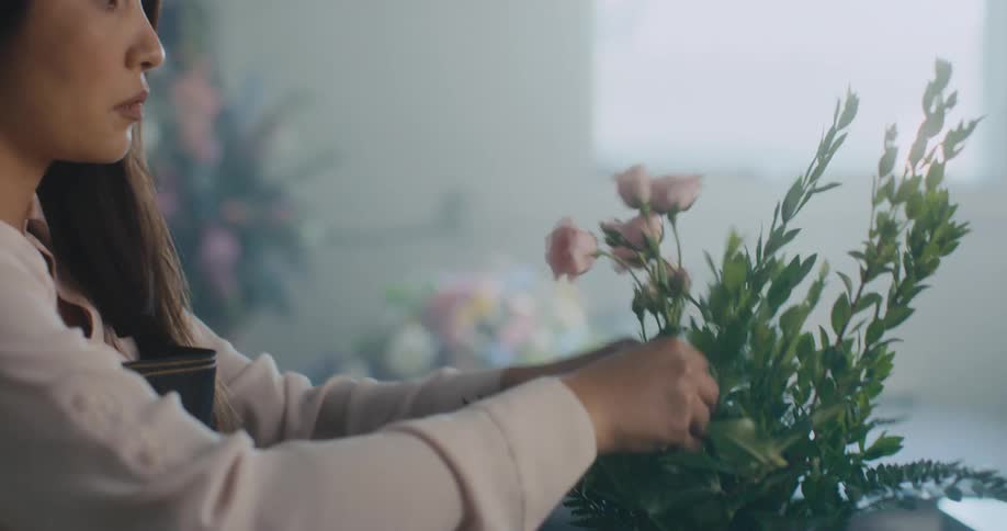 A florist smiles after working on a floral arrangement in her shop