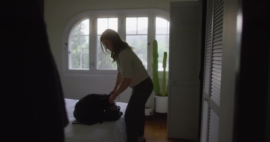 A woman putting on a backpack