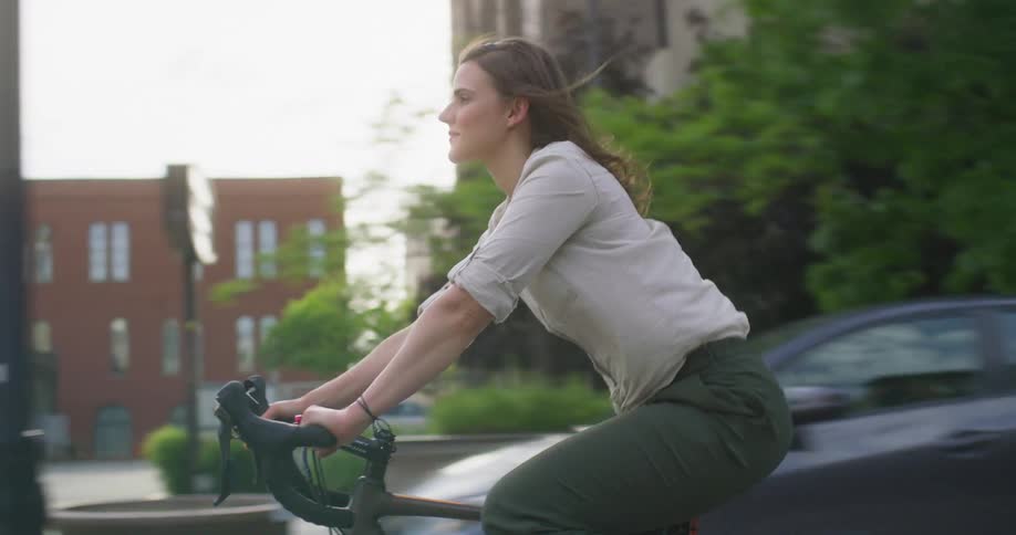 A woman riding a bicycle on a city street on a sunny summer day